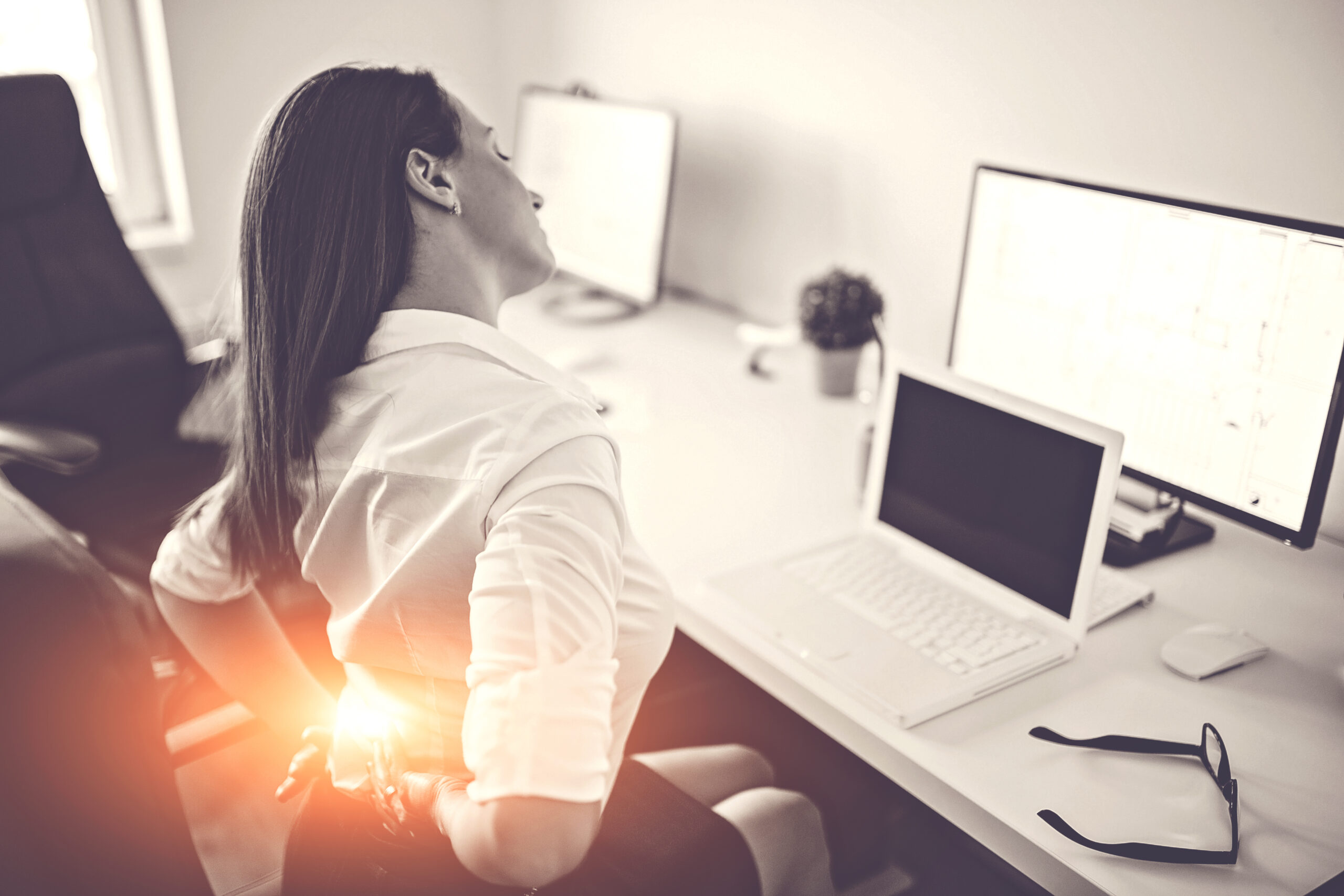 A woman at a desk with lower back pain